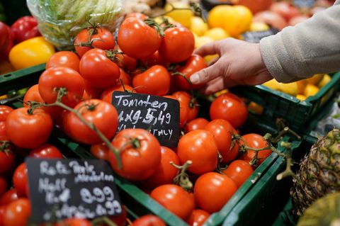 Ein Mann greift nach Tomaten im Supermarkt