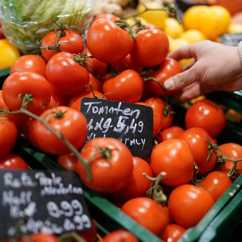 Ein Mann greift nach Tomaten im Supermarkt