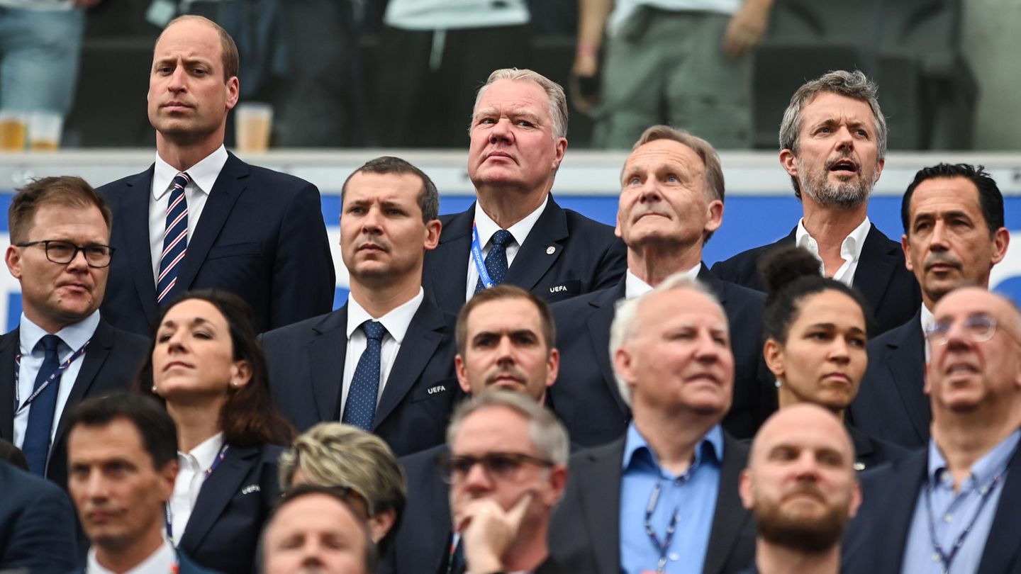 Dänemarks König Frederik X. (r) und William, Prinz von Wales, zwischen Fußball-Funktionären auf der Tribüne