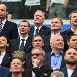 Dänemarks König Frederik X. (r) und William, Prinz von Wales, zwischen Fußball-Funktionären auf der Tribüne