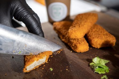 Mit einem großen Messer werden Fischstäbchen kleingeschnitten