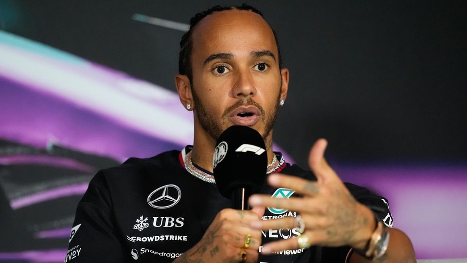 Formel 1 Fahrer Lewis Hamilton spricht in ein Mikro und gestikuliert mit der linken Hand