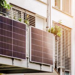 Mehrere Balkonkraftwerke an einem Gitterbalkon in der Sonne.