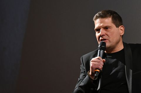 Jan Ullrich sitzt auf einer Bühne und spricht in ein Mikrofon
