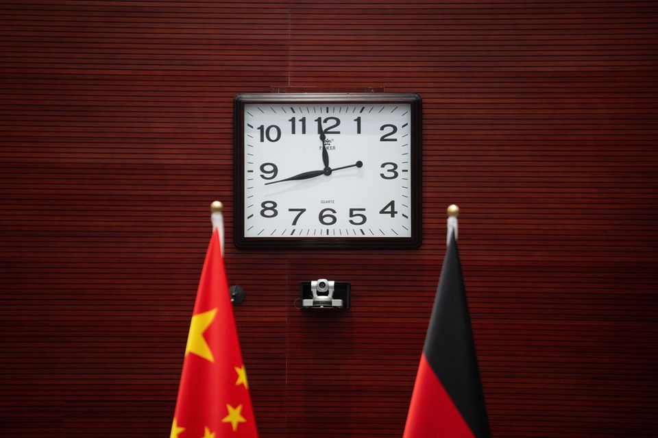 Vor einer großen quadratischen Uhr sind die deutsche und die chinesische Flagge zu sehen