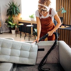 Frau reinigt eine Couch mit einem Nassauger