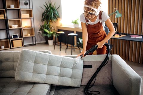 Frau reinigt eine Couch mit einem Nassauger