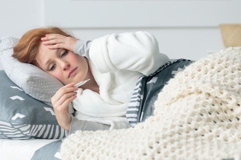 Frau liegt mit Fieber im Bett