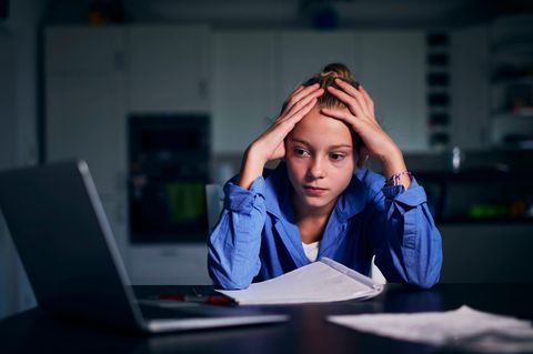 Stress mit Schulnoten: Mädchen sitzt mit Kopf in den Händen gestützt vor dem Laptop