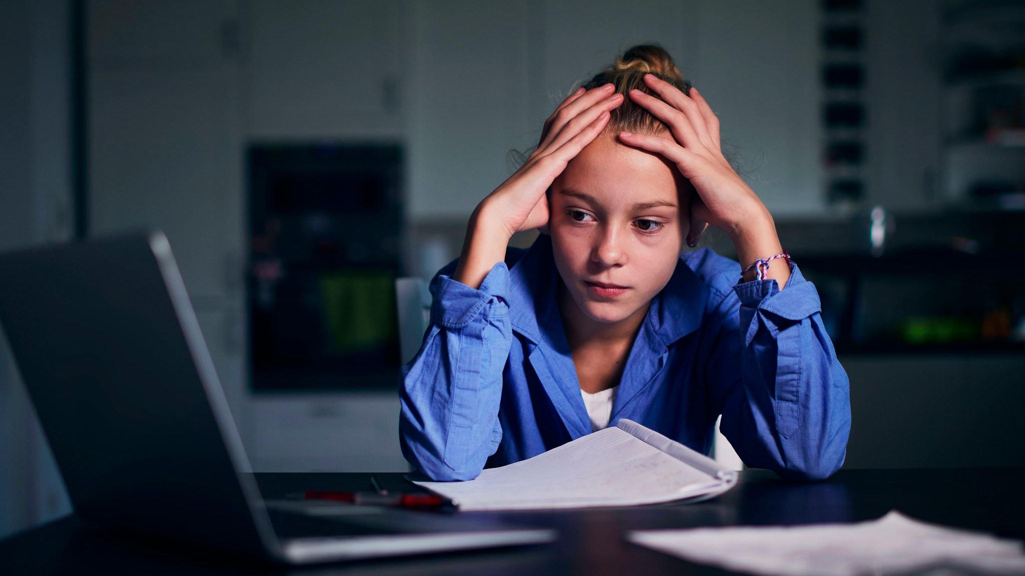 Stress mit Schulnoten: Mädchen sitzt mit Kopf in den Händen gestützt vor dem Laptop