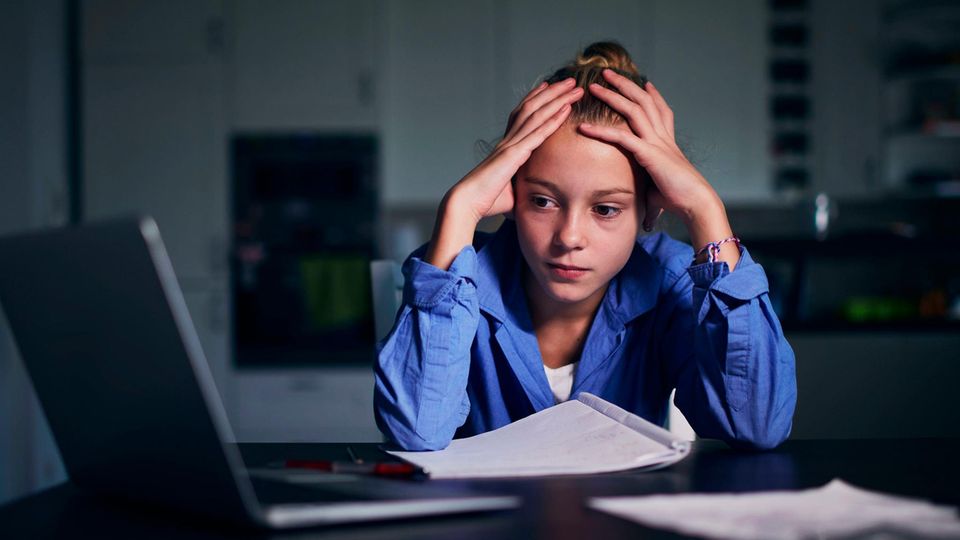 Stress dovuto ai voti scolastici: donna seduta davanti al portatile con la testa tra le mani