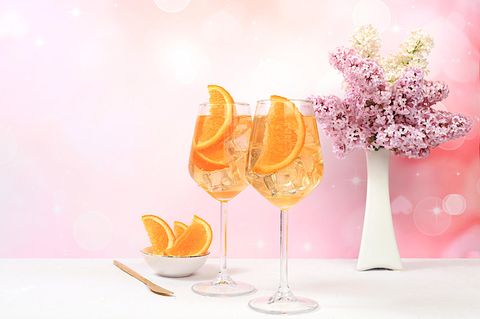 Alkoholischer Cocktail in Gläsern auf hellem Hintergrund mit Fliederstrauß