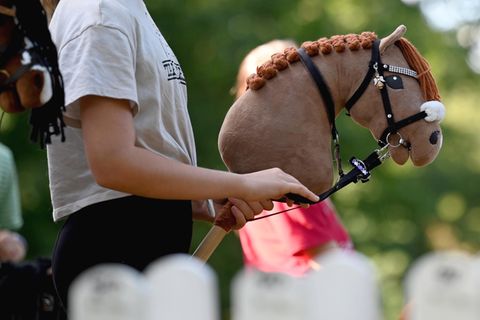 Hobby Horsing: Ein Mädchen hält ihr beiges Hobby Horse