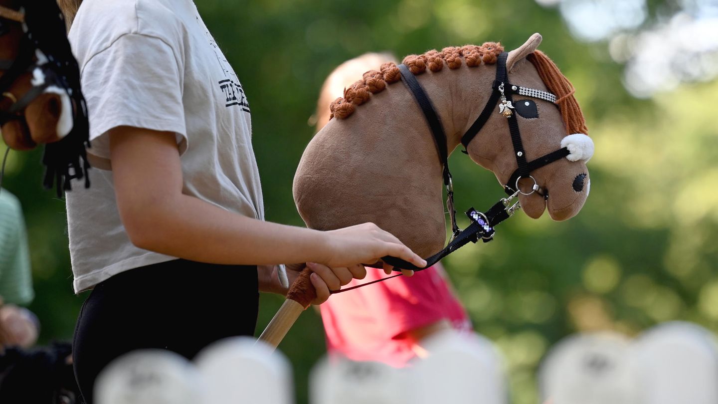 Hobby Horsing: Ein Mädchen hält ihr beiges Hobby Horse Hobby Horsing: Ein Mädchen hält ihr beiges Hobby Horse
