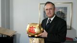Der ehemalige Bundesfinanzminister Hans Eichel hält in seinem Büro ein großes Sparschwein in der Hand