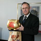 Der ehemalige Bundesfinanzminister Hans Eichel hält in seinem Büro ein großes Sparschwein in der Hand