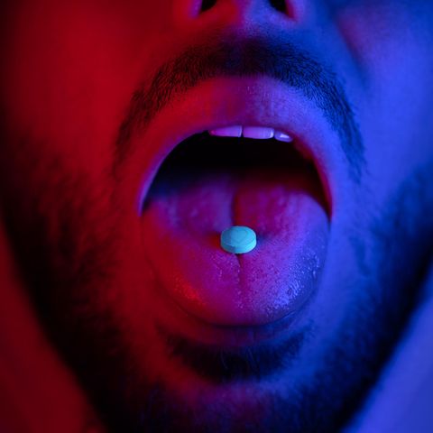 Nahaufnahme des Mundes des Mannes, der Ecstasy-Drogen schluckt (Symbolbild)