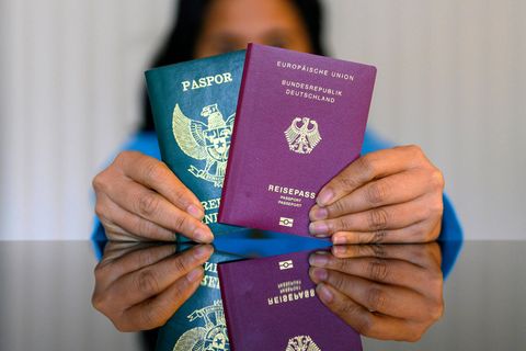Eine Frau hält einen indonesischen und einen deutschen Pass.