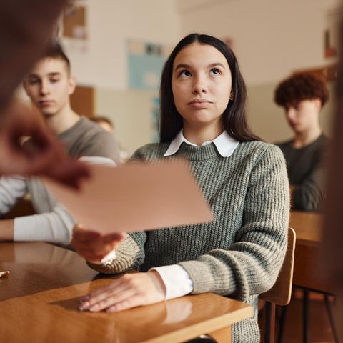 Teenager-Schülerin, die ihr Zeugnis in einer Klasse der Schule erhält.