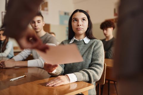 Teenager-Schülerin, die ihr Zeugnis in einer Klasse der Schule erhält.