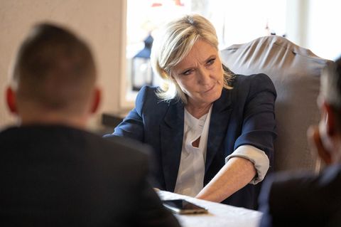 Marine le Pen sitzt auf einem Stuhl und schaut zur Seite