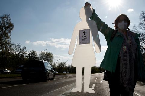 Eine Frau hält eine weiße Papier Silhuette in der Hand mit der Aufschrift Kind 11 jahre