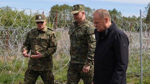 Polens Ministerpräsident Donald Tusk (r-l) zusammen mit Befehlshabern des Grenzschutzes am Zaun zu Belarus