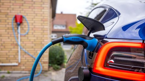 Ein E-Auto wird an einer Wallbox an einem Wohnhaus geladen