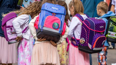 Mädchen von hinten mit Schulranzen auf dem Rücken