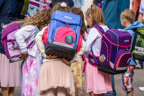 Mädchen von hinten mit Schulranzen auf dem Rücken