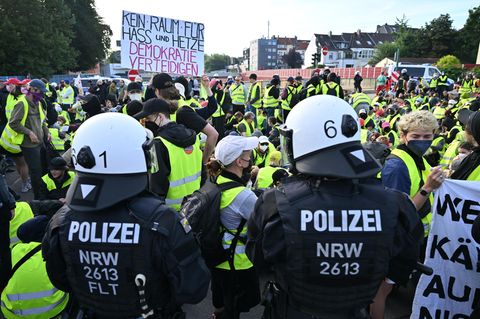 Demonstranten stehen und sitzen auf einer Zufahrtsstraße zum Gelände des AFD-Parteitags – einige halten ein Schild mit der Aufschrift "Kein Raum für Hass und Hetze – Demokratie verteidigen"