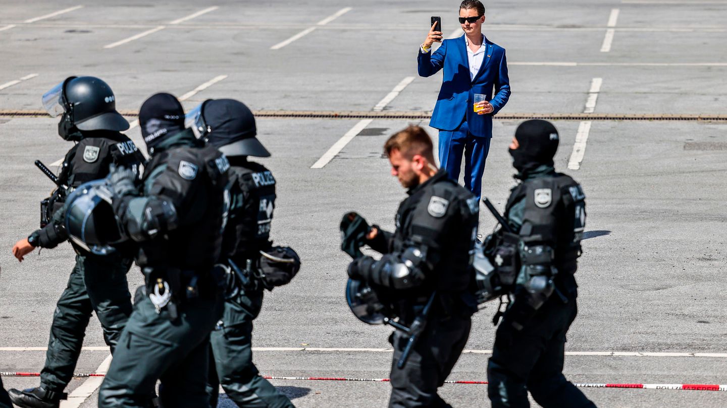 Ein Abgeordneter der AfD steht auf dem Parkplatz der Grugahalle und filmt mit einem Smartphone die Gegendemonstration und Polizisten