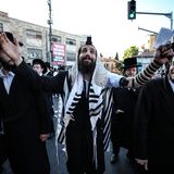 Unter den Demonstranten ist auch dieser Mann in traditioneller Gebetskleidung mit Hand- und Kopftefillin – Lederriemen und kleine Kästchen, die auf Pergament handgeschriebene, spezielle Torastellen enthalten – sowie Tallit, den Gebetsmantel oder auch Gebetsschal 