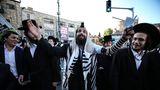 Unter den Demonstranten ist auch dieser Mann in traditioneller Gebetskleidung mit Hand- und Kopftefillin – Lederriemen und kleine Kästchen, die auf Pergament handgeschriebene, spezielle Torastellen enthalten – sowie Tallit, den Gebetsmantel oder auch Gebetsschal 