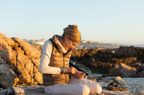 Urlaub: Frau am Strand checkt ihr Smartphone