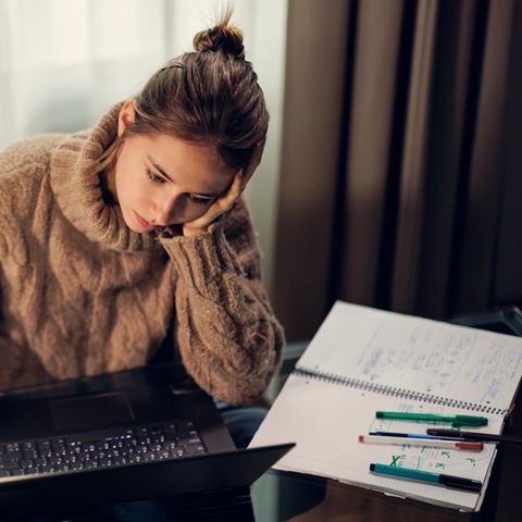 Teenager-Mädchen studiert an einem modernen Glastisch. Dunkler und kalter Spätherbstabend.