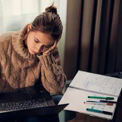 Teenager-Mädchen studiert an einem modernen Glastisch. Dunkler und kalter Spätherbstabend.