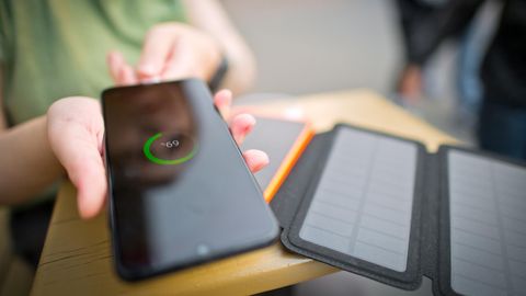 Mann mit Solarzellen, um Smartphone im Wald zu versorgen