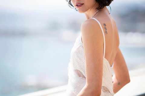 Portrait von Margaret Qualley, wie sie im weißen Kleid an einer Reling lehnt