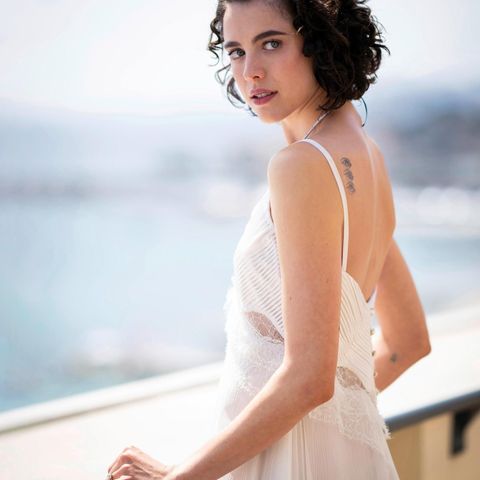 Portrait von Margaret Qualley, wie sie im weißen Kleid an einer Reling lehnt