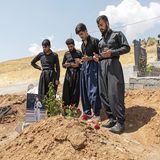 Männliche Verwandte beten an dem Grab eines erschossenen Iraners