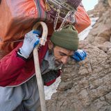 Schmuggel Iran: Alter Mann mit schwerem Gepcäk auf dem Rücken beim Anstieg