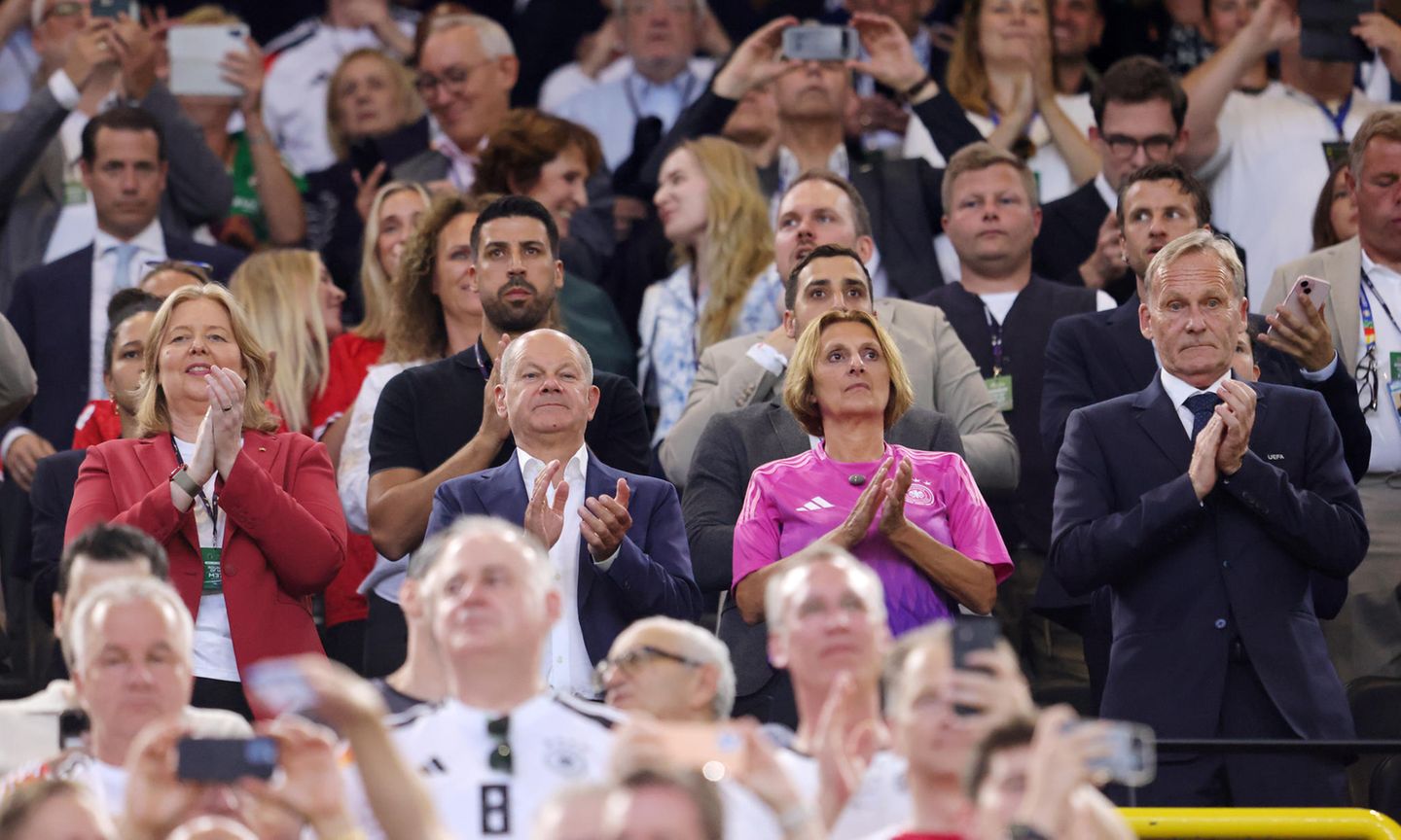 Menschen stehen bei der EM im Stadion auf der Tribüne und klatschen