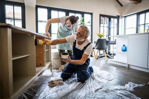 Ein Handwerker beizt einen Schrank