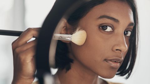 Make-up Pinsel reinigen: Eine Frau hält sich einen Pinsel an die Wange.