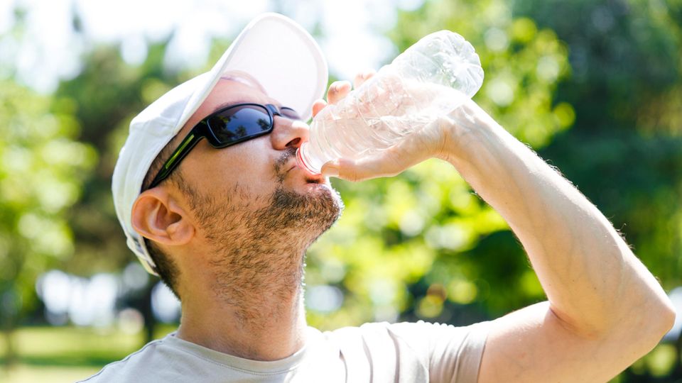 Sonnenschutz beim Joggen: Läufer mit Cap und Sonnebrille trinkt aus einer Wasserflasche