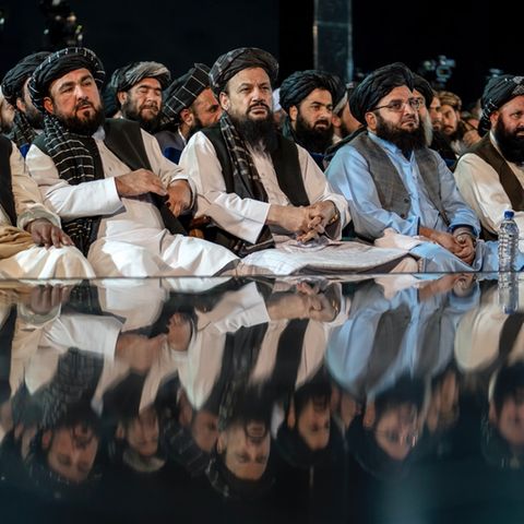 Mehrere Taliban sitzen auf dem Boden.