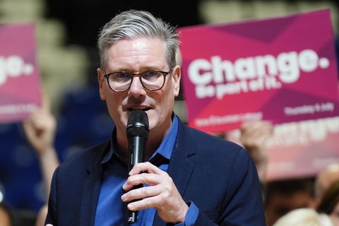 Keir Starmer mit Mikrofon vor einem Wahlplakat