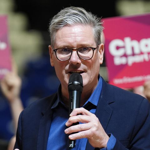 Keir Starmer mit Mikrofon vor einem Wahlplakat