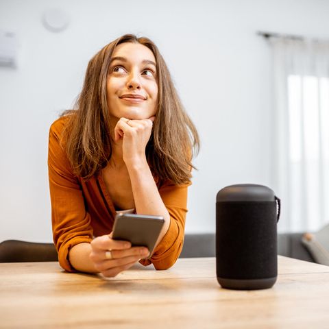 Balkonkraftwerk und Smart Home: Frau mit Handy und Smarthome-Hub am Küchentisch.